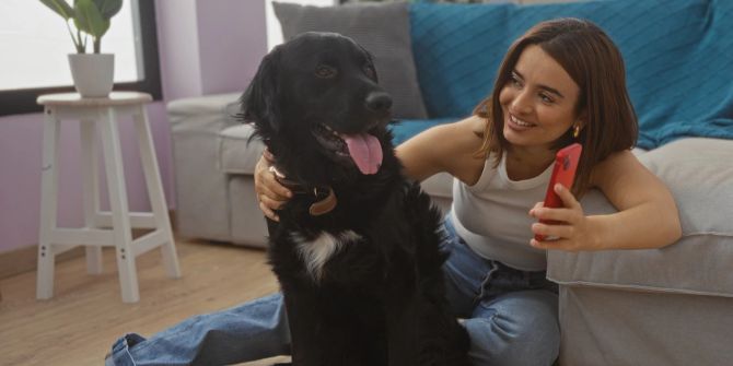Hund und junge Frau mit Smartphone