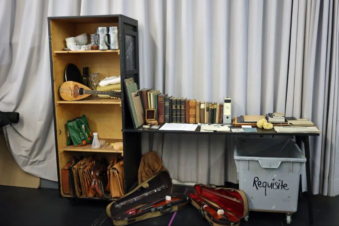 Ein Blick in die Requisiten des Musicals. Requisiten Geige Bücher Tisch