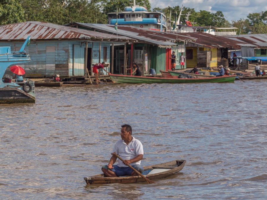 Mann Kanu Amazonas Ufer mit Häusern