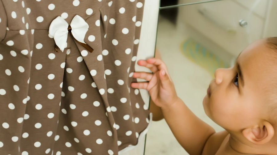 kleines Mädchen will gepunktetes Kleidchen anziehen