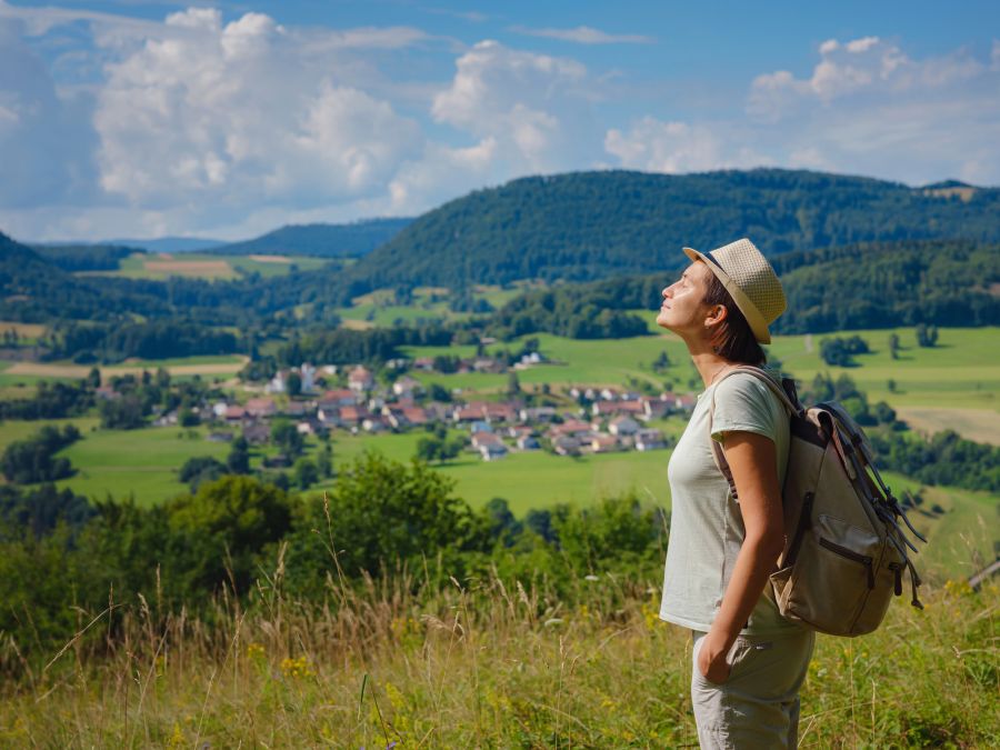 Frau mit Rucksack geniesst frische Luft und Sonne im Freien