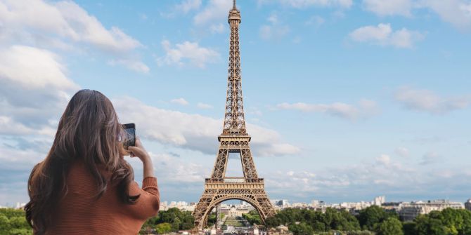 Touristin mit Smartphone fotografiert Eiffelturm