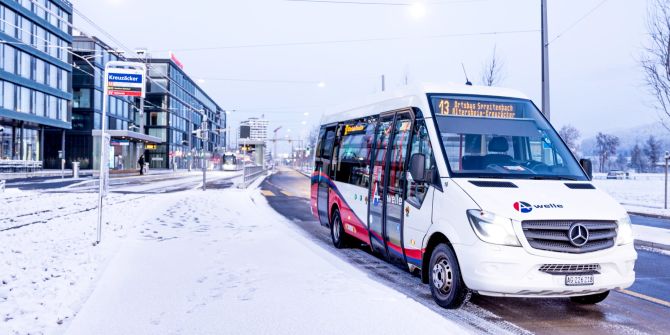 Ein Kleinbus auf einer verschneiten Strasse.