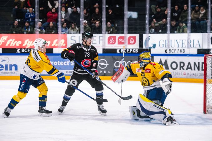 Die Davos Dominik Egli und Sandro Aeschlimann im Duell mit Fribourgs Sandro Schmid. HC Davos