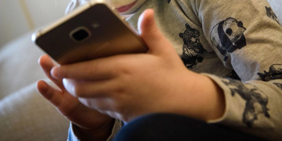 Ein kleines Mädchen schaut auf das Display eines Smartphones. Dutzende US-Bundesstaaten ziehen gegen den Facebook-Konzern Meta vor Gericht. Sie werfen dem Unternehmen vor negative Folgen für Kinder und Jugendliche zu ignorieren, um mehr Gewinn zu machen.