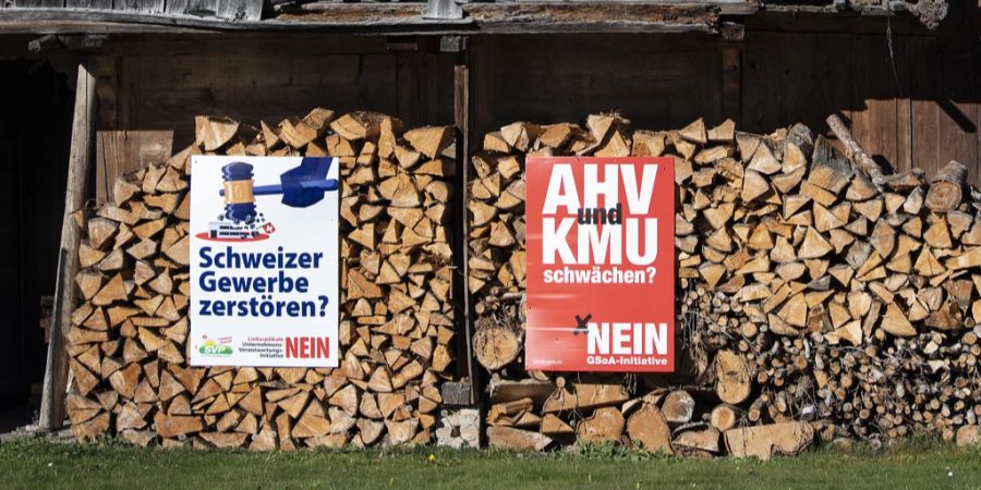 Plakate gegen die Kriegsgeschäfte- und Konzernverantwortungsinitiative hängen an einem Holzstapel, im Herbst 2020 am Kreuzweg oberhalb Steffisburg BE.