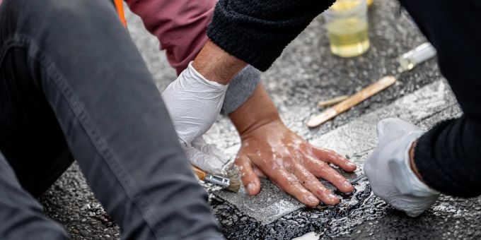 Eien Aktivistin der Letzten Generation hat sich auf die Strasse geklebt. Ein Polizist versucht, ihre Hand vom Asphalt zu lösen. Eien Aktivistin der Letzten Generation hat sich auf die Strasse geklebt. Ein Polizist versucht, ihre Hand vom Asphalt zu lösen.