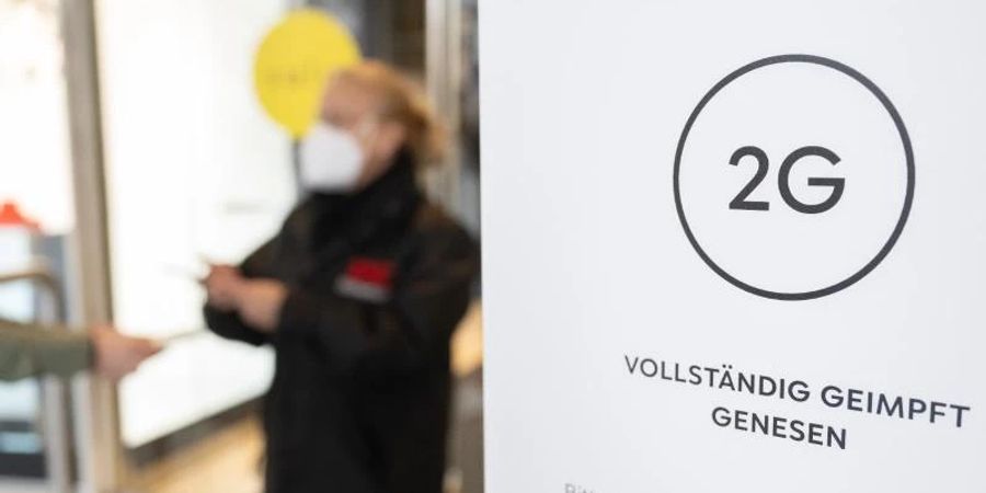 Eine Mitarbeiterin eines Stuttgarter Kaufhauses kontrolliert den Impfnachweis einer Kundin. Foto: Bernd Weissbrod/dpa