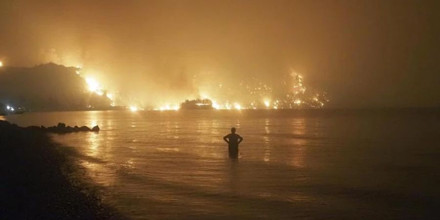 Ein Mann beobachtet im August 2021, wie sich Waldbrände dem Strand von Kochyli in der Nähe des Dorfes Limni auf der Insel Evia (Griechenland) nähern. Foto: Thodoris Nikolaou/AP/dpa