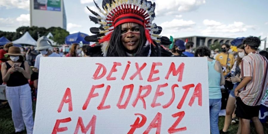 Ein Indigener hält ein Protestplakat mit der Aufschrift «Lasst den Wald in Ruhe»