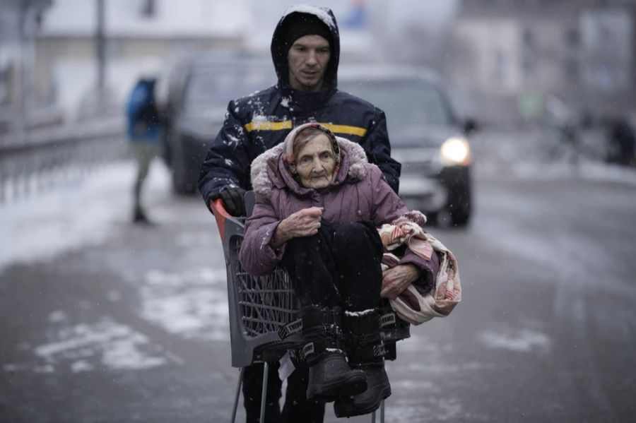 Eine ältere Frau wird in der Ukraine in einem Einkaufswagen durch die Strassen gefahren.