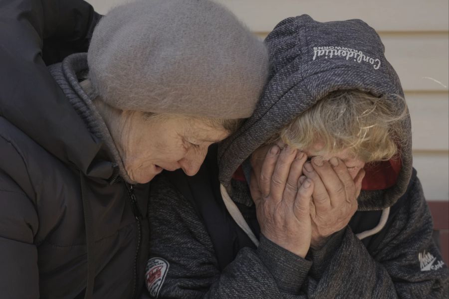 Eine Nachbarin tröstet Natalja, deren Ehemann und Neffe von russischen Streitkräften getötet wurden, während sie in ihrem Garten in Butscha, Ukraine, weint, Montag, 4. April 2022.