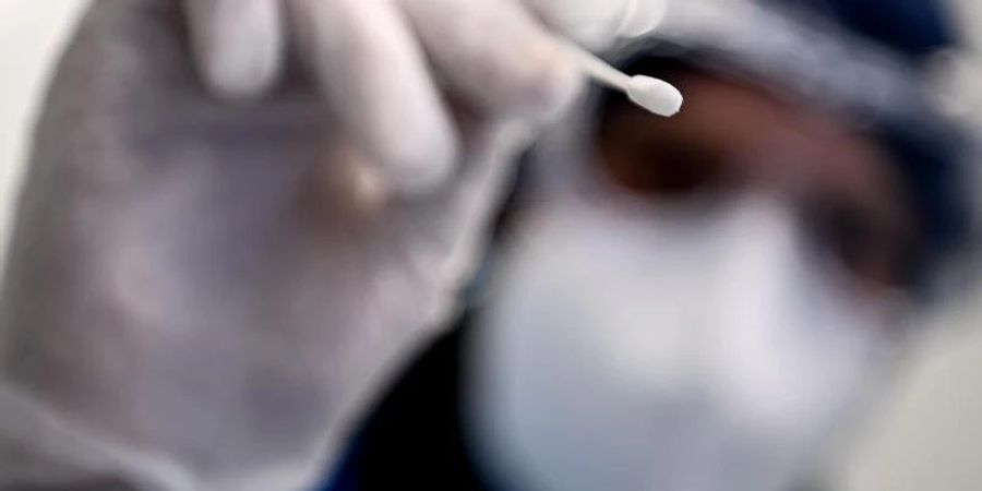 Ein Arzt beim Gesundheitsamt Neukölln hält ein Teststäbchen für einen PCR-Test in der Hand. Foto: Britta Pedersen/dpa-Zentralbild/dpa
