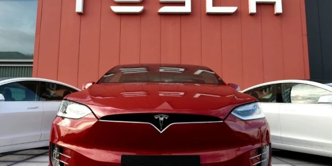 Tesla-Autos vor Firmenlogo Tesla-Autos vor Firmenlogo