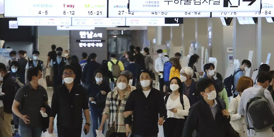 Menschen mit Mundschutz gehen am Flughafen Gimpo durch die Gänge des Inlandsterminals. Die Behörden haben alle Flugzeugpassagiere auf Grund der Corona-Pandemie zum Tragen von Gesichtsmasken aufgefordert. Foto: Ahn Young-Joon/AP/dpa