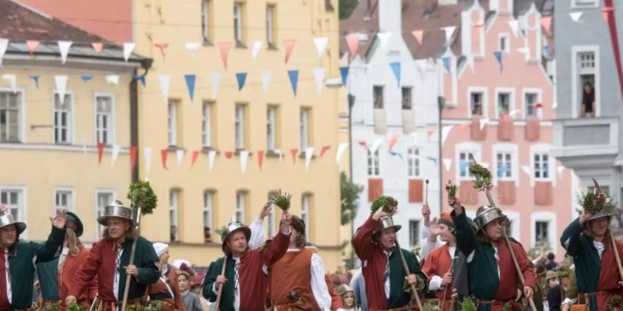 Teilnehmer in historischer Kleidung gehen während dem Umzug der Landshuter Hochzeit im Jahr 2017 durch die Altstadt. Foto: picture alliance / Armin Weigel/dpa