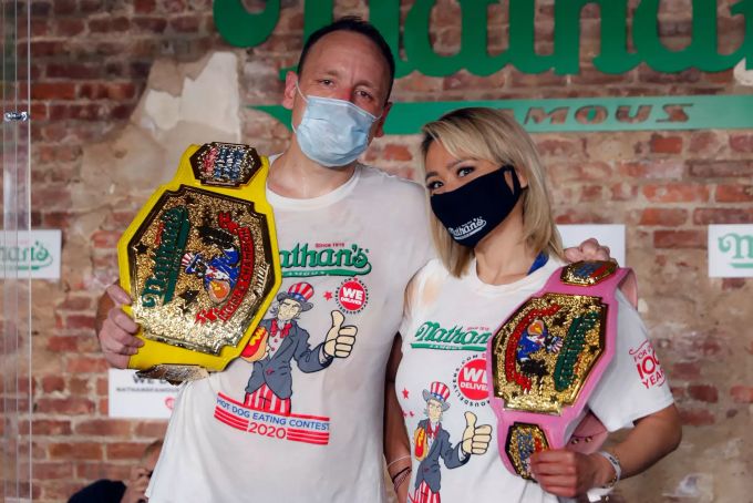 Miki Sudo (r) und Joey Chestnut, Gewinner und Gewinnerin des Hotdog-Wettessens, stehen mit Mundschutz und Siegergürtel für ein Foto bereit. Beim Hotdog-Wettessen im New Yorker Vergnügungspark Coney Island hat der Serien-Champion Joey Chestnut einen neuen Rekord aufgestellt. hotdogs