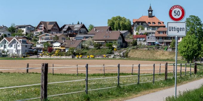 Ortsschild Uttigen mit Blick auf das alte Schulhaus und das Oberdorf - Uttigen Ortsschild Uttigen mit Blick auf das alte Schulhaus und das Oberdorf - Uttigen